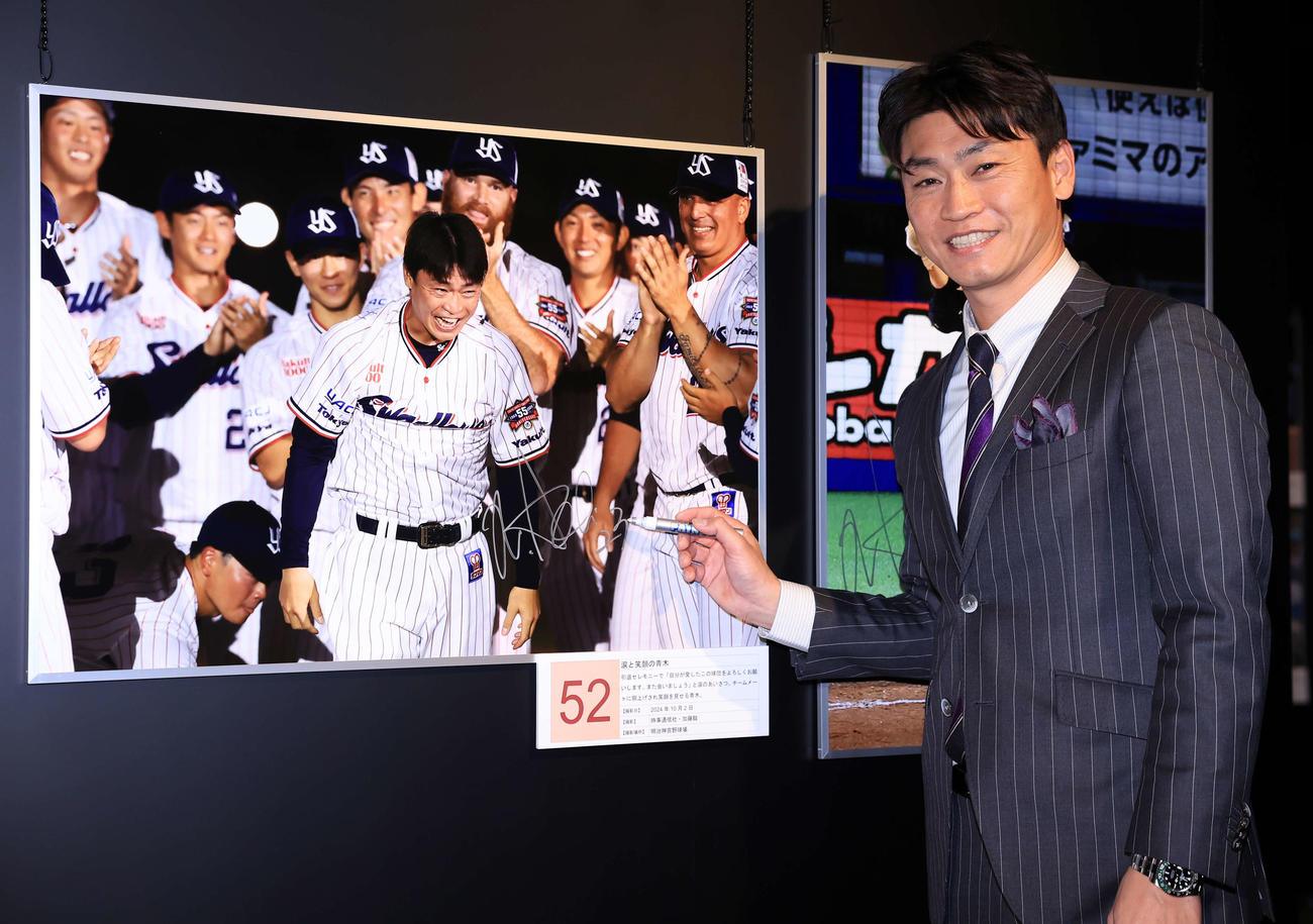 「野球報道写真展2024」のゲストで訪れた青木宣親氏は、自身の写真にサインを入れて笑顔（撮影・浅見桂子）