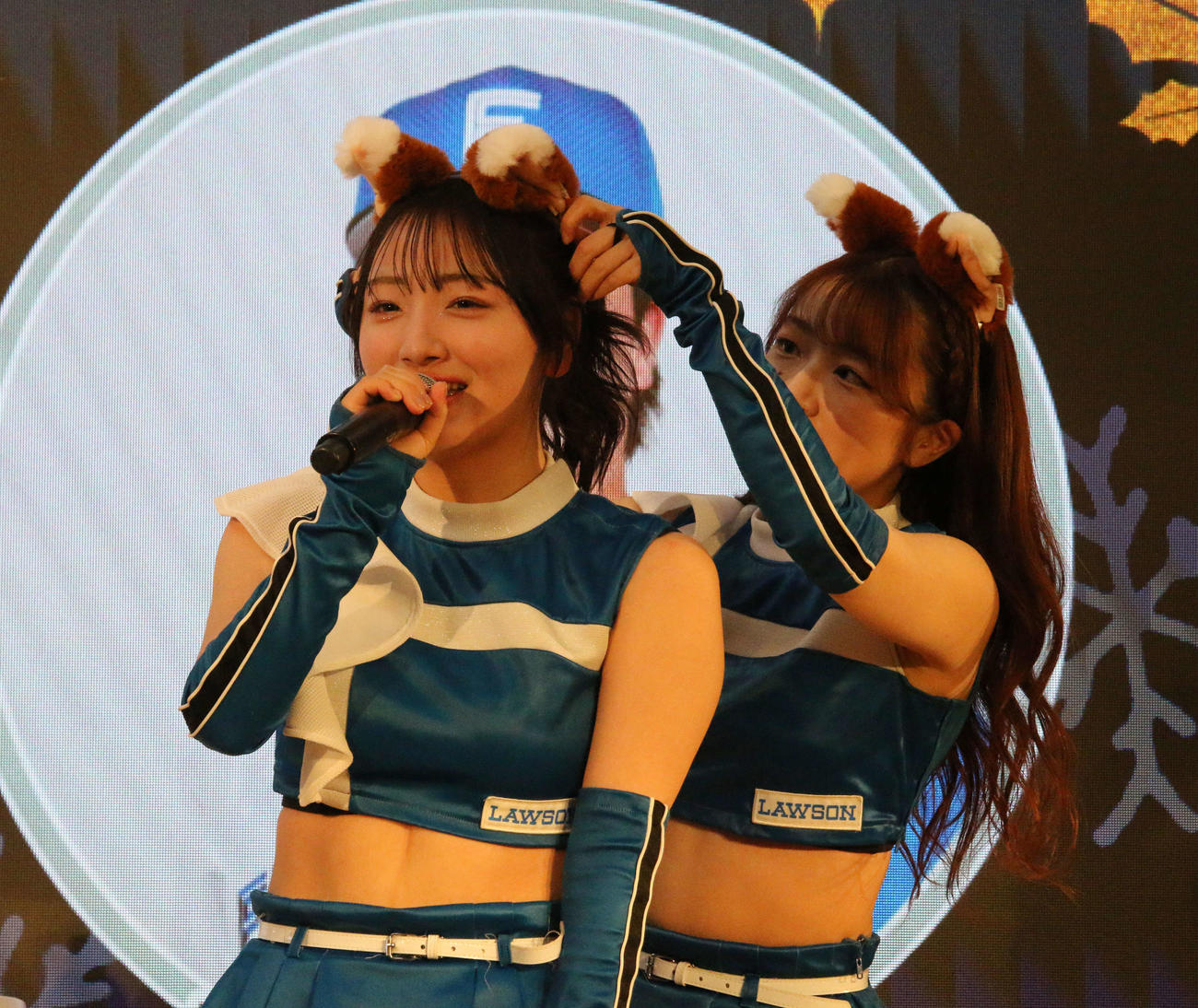 三井アウトレットパーク札幌北広島できつねダンスを披露する前にMC中のファイターズガール田中心優（左）にきつねの耳を装着する上山真奈（撮影・木下大輔）