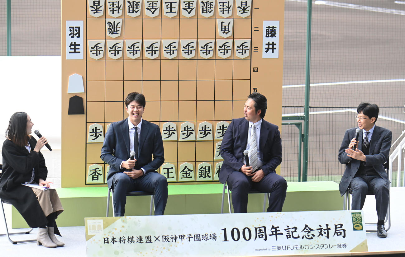 100周年記念対局のスペシャルトークショーで谷川十七世名人（右）から初段免状を贈られ、喜ぶ阪神才木（左から2人目）。右から2人目は阪神OB井川（撮影・滝沢美穂子）