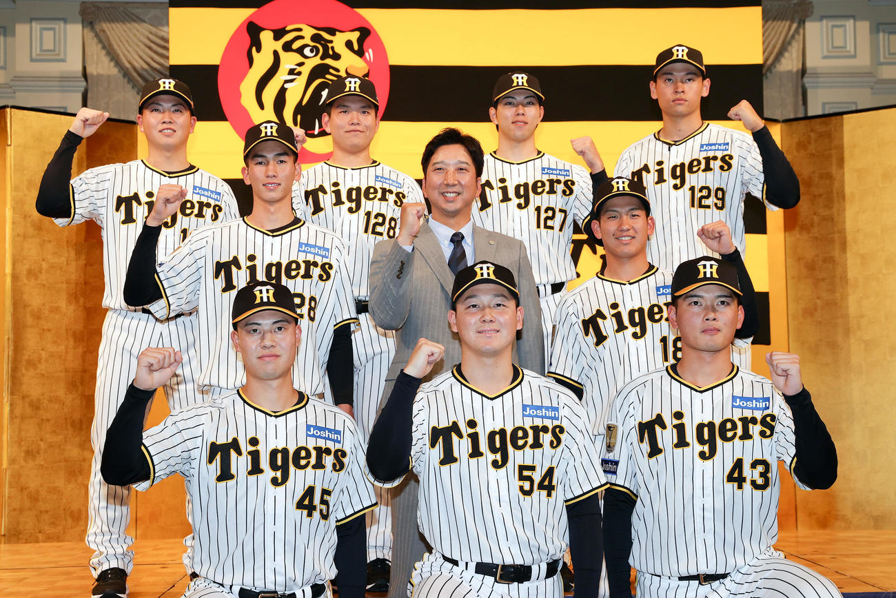 藤川球児監督（中央）を中心にガッツポーズで写真に納まる阪神の新人選手たち。前列左から佐野、木下、町田、中列左から今朝丸、1人おいて伊原、後列左から川崎、嶋村、工藤、早川（撮影・前田充）