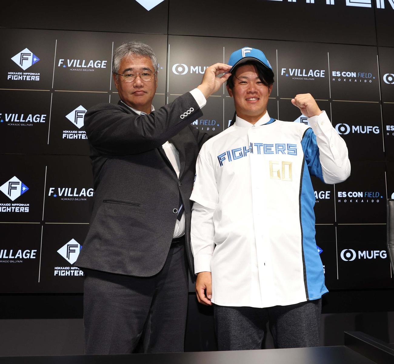 日本ハムに移籍し木田GM代行（左）に帽子をかぶせてもらう吉田（撮影・黒川智章）