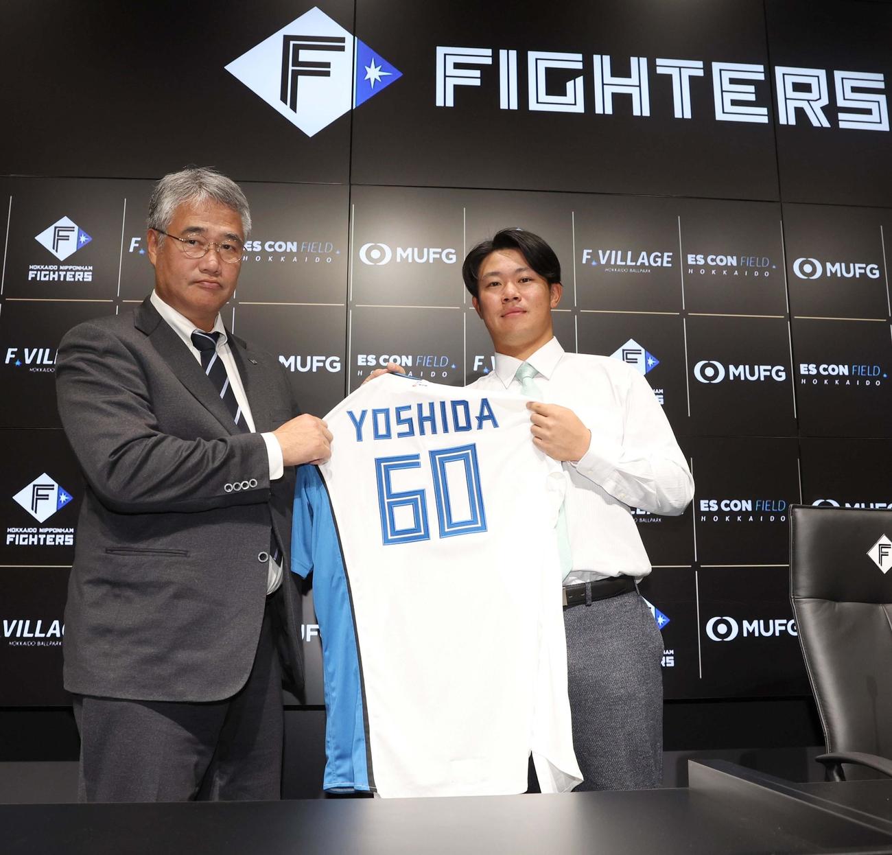 日本ハムに移籍し木田GM代行（左）と背番号「60」のユニホームを持つ吉田（撮影・黒川智章）