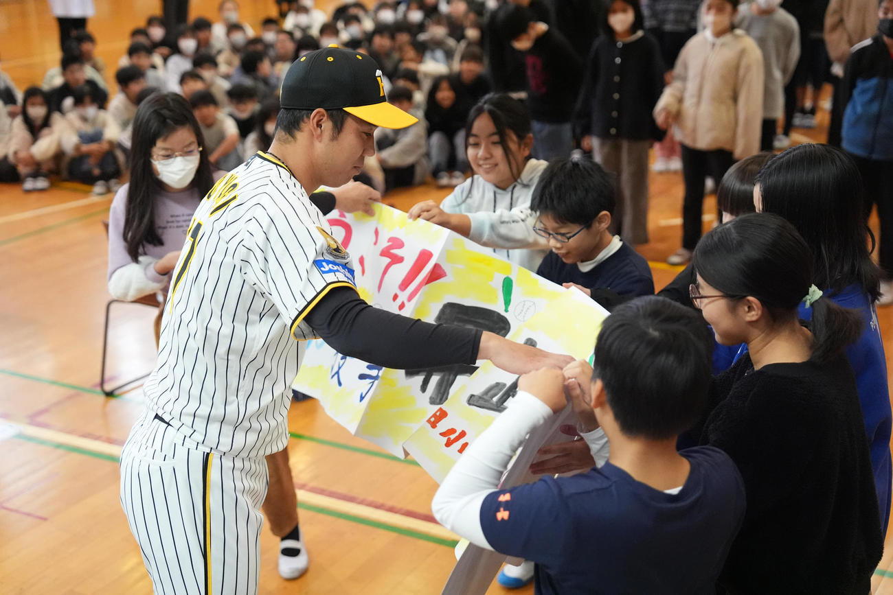 潮田小学校の子どもたちから横断幕を受け取る阪神青柳（撮影・鈴木みどり）