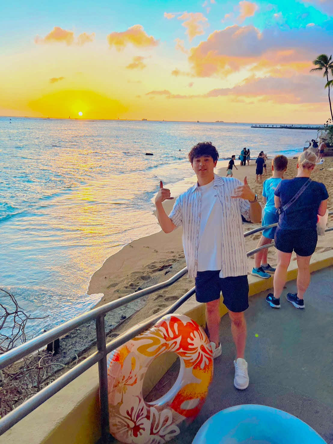 夕暮れのビーチでアロハポーズを決める川瀬（撮影・只松憲）