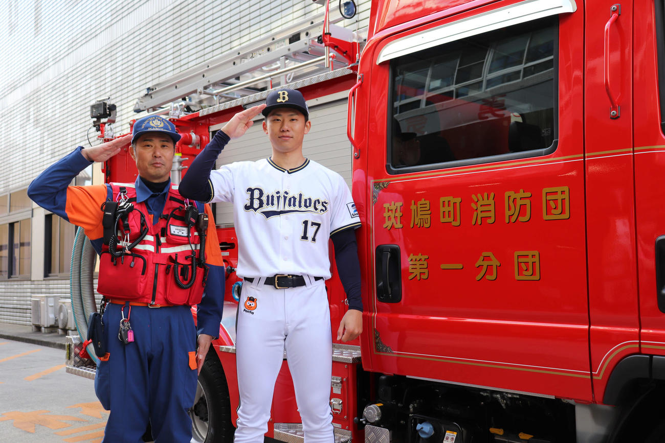 オリックス曽谷（右）は出身の奈良・斑鳩町の役場勤務で消防団員も務める父博一さんと敬礼（撮影・大池和幸）