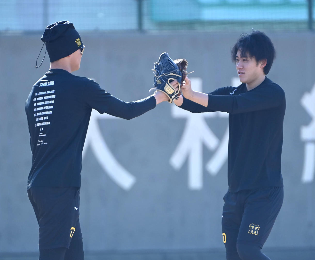 キャッチボールを終えグラブを合わせる（左から）阪神及川、富田（撮影・石井愛子）