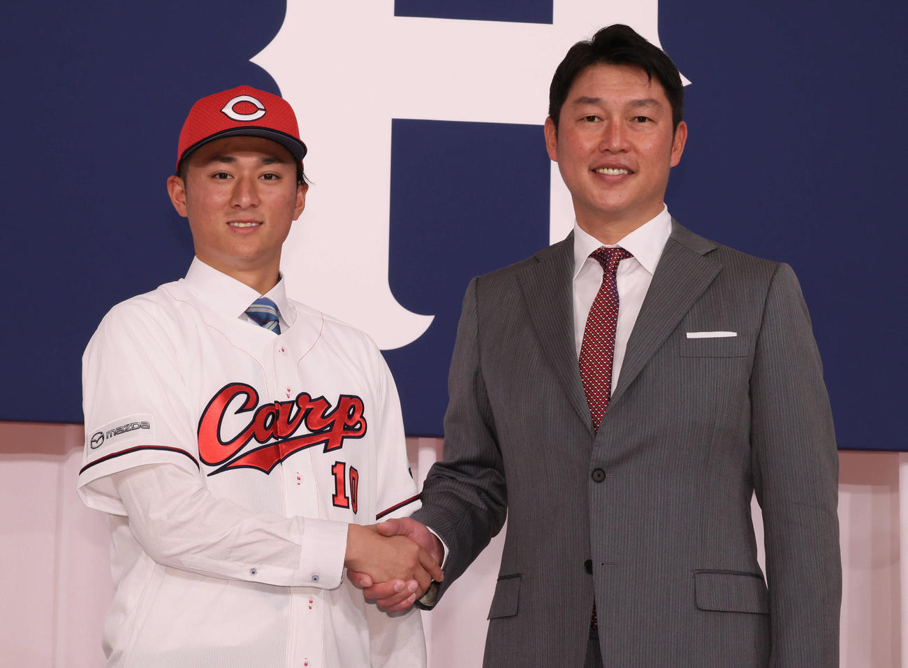 新入団選手会見で、新井監督と握手するドラフト1位の佐々木（左）（撮影・加藤孝規）