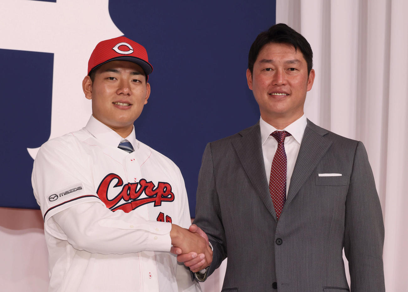 新入団選手会見で、新井監督と握手するドラフト4位の渡辺（左）（撮影・加藤孝規）
