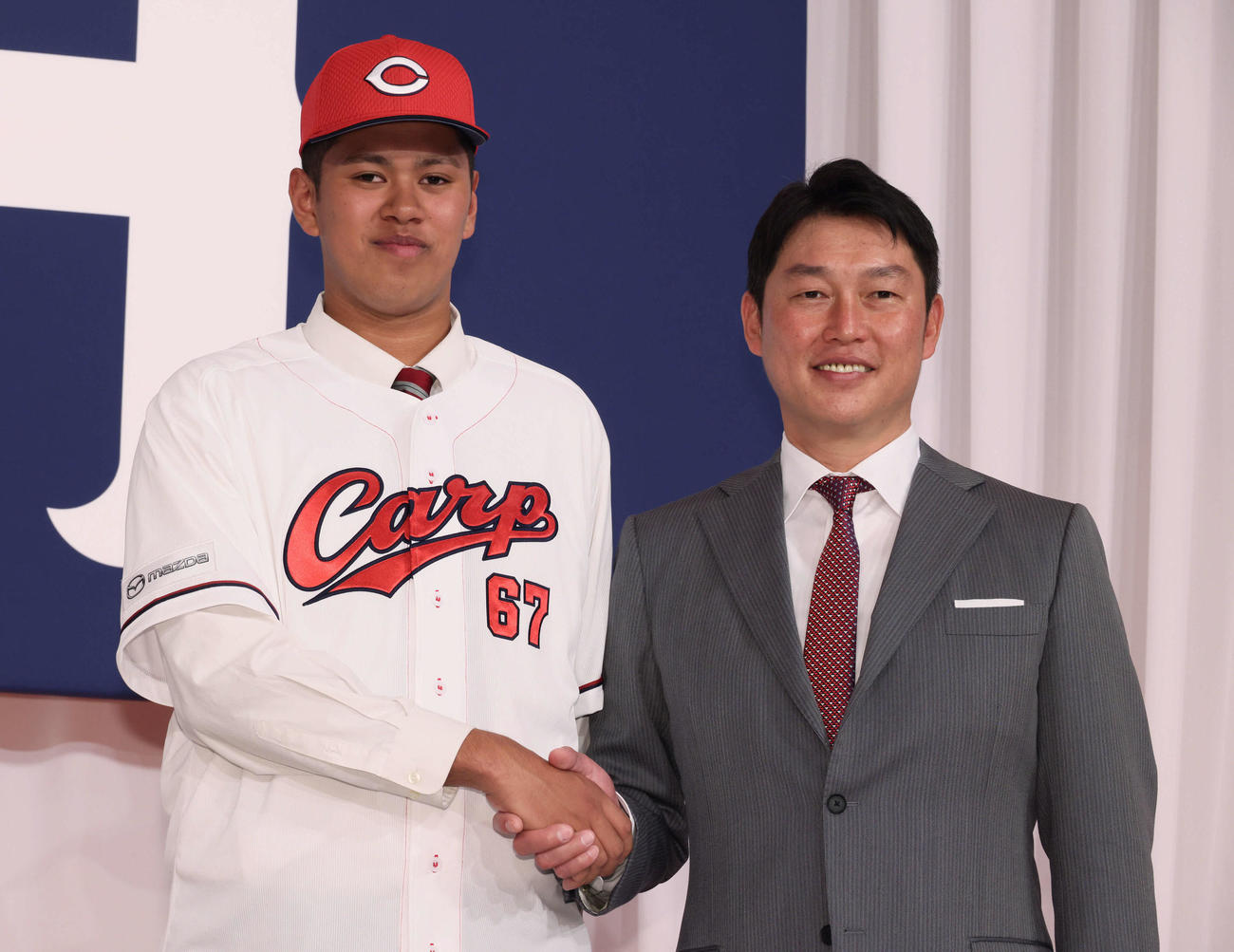 新入団選手会見で、新井監督と握手するドラフト5位の菊地（左）（撮影・加藤孝規）
