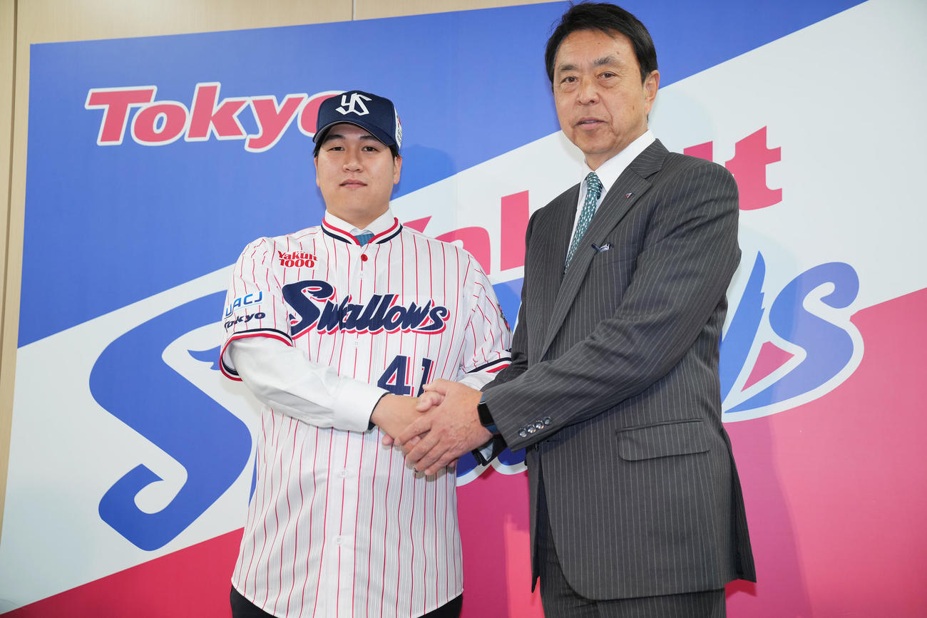 入団会見を行いヤクルト小川GM（右）と握手を交わす矢崎（撮影・垰建太）