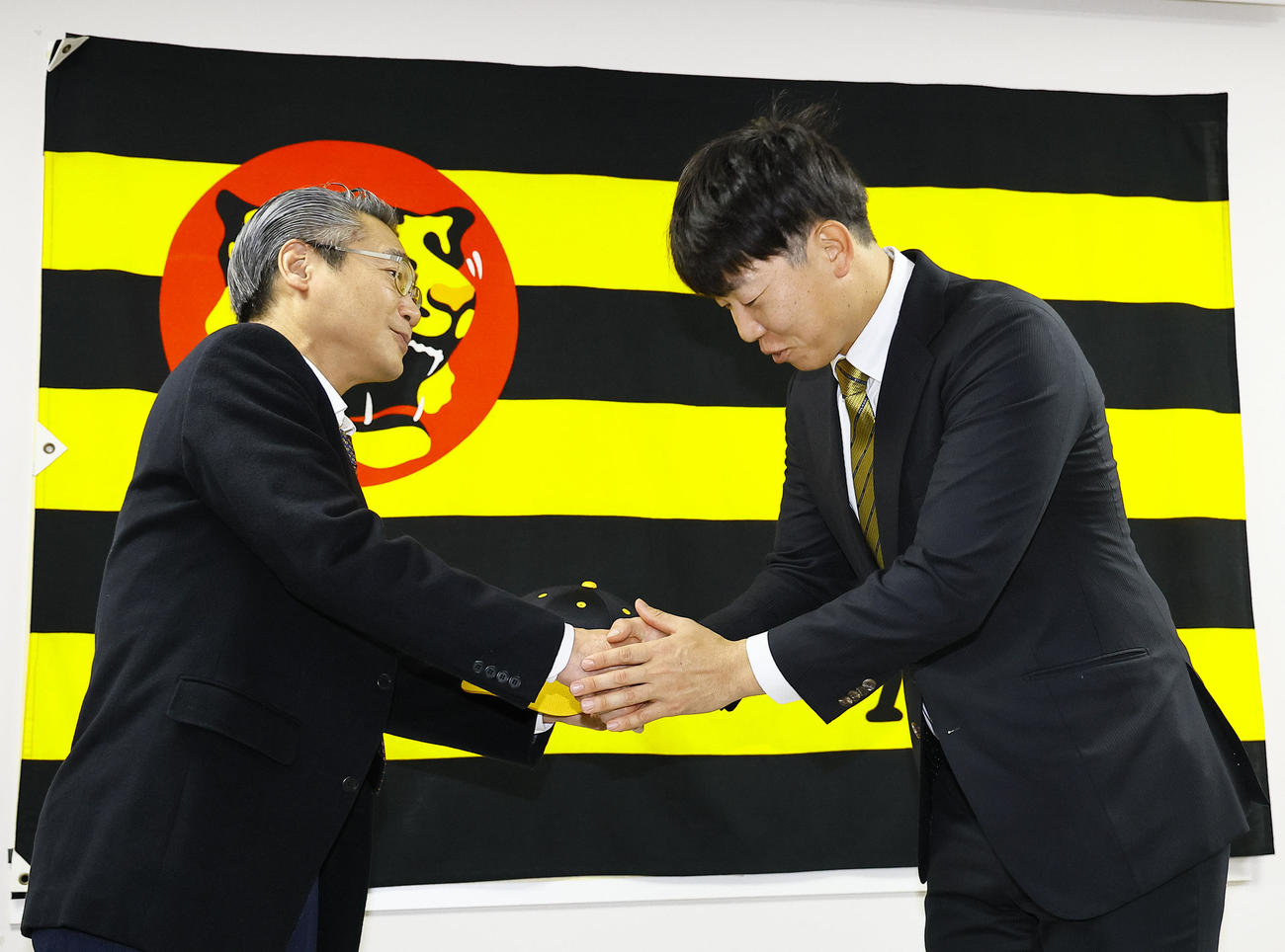 入団会見で阪神嶌村球団本部長（左）と握手を交わす畠（撮影・藤尾明華）