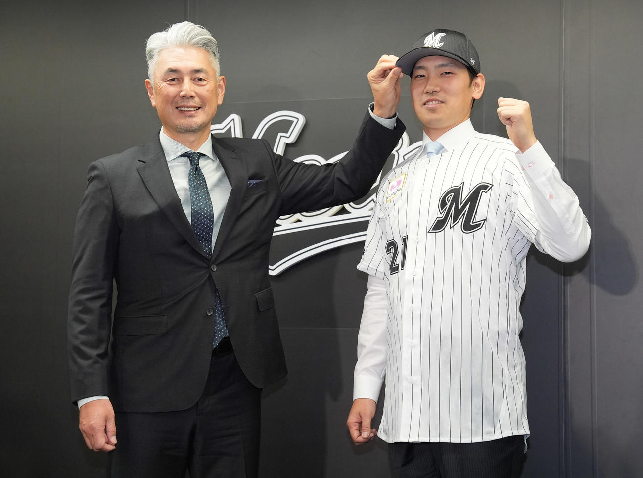 入団会見でユニホームを着てガッツポーズするロッテ石川柊。左は吉井監督（撮影・鈴木みどり）