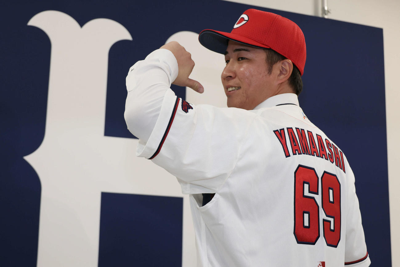 現役ドラフトでオリックスから広島に移籍した山足は入団会見で背番号を披露（撮影・加藤孝規）