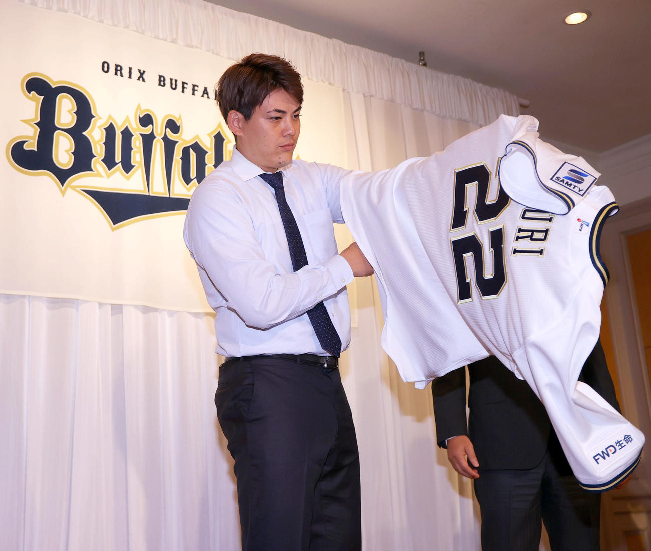 オリックス入団会見を終えた九里はフォトセッションで背番号「22」のユニホームに袖を通す（撮影・上山淳一）
