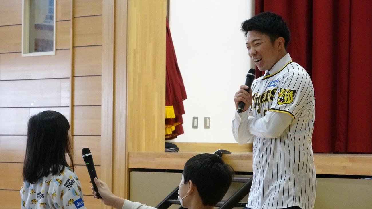 阪神石井（右）は秋田市立旭川小学校で児童の質問に笑顔で答える（球団提供）