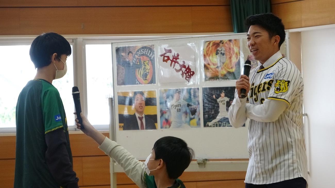 阪神石井（右）は秋田市立旭川小学校で児童の質問に笑顔で答える（球団提供）