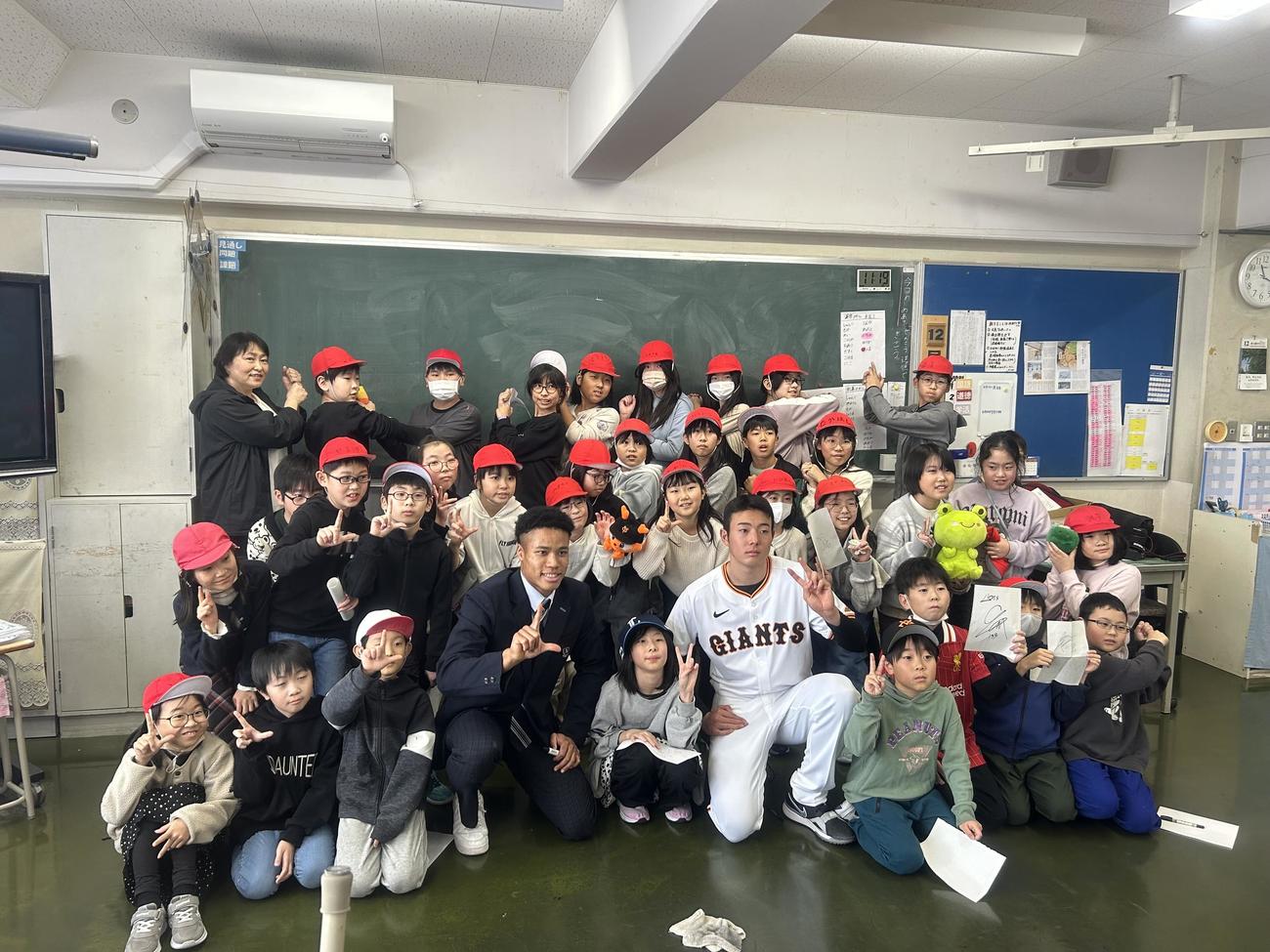 ウメビンユオ（前列中央左）と石田（同右）は母校・旭川啓明小の子どもたちに囲まれる（提供・石田威仁氏）