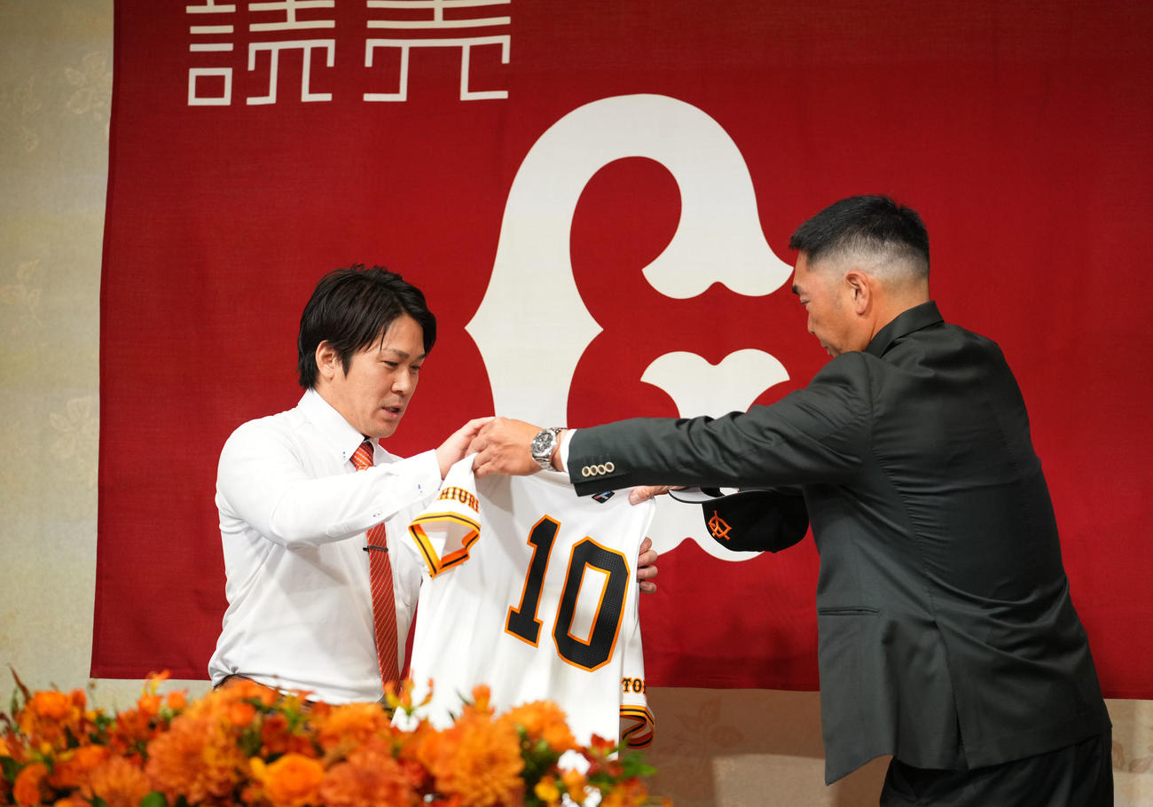 入団会見で巨人阿部（右）からユニホームを受け取る甲斐（撮影・横山健太）