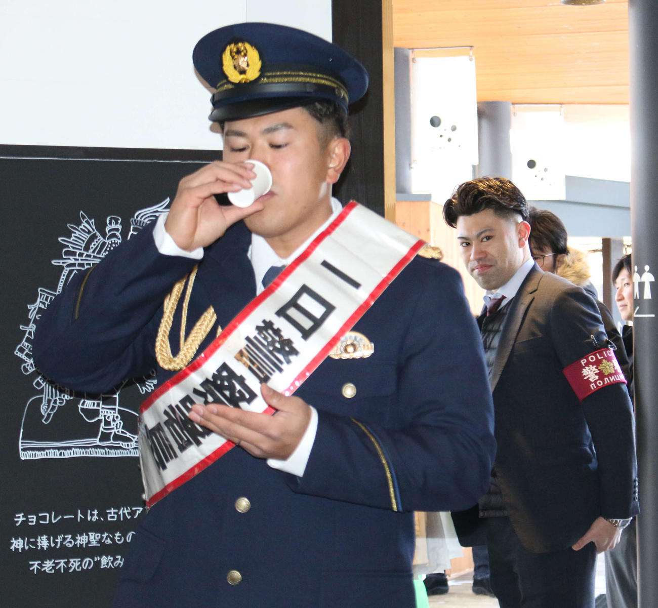 北海道・札幌にある豊平警察署の一日警察署長を務め、商業施設で歳末防犯パトロールを行った日本ハム今川（左）を見守る同署署員の弟駿さん（撮影・木下大輔）