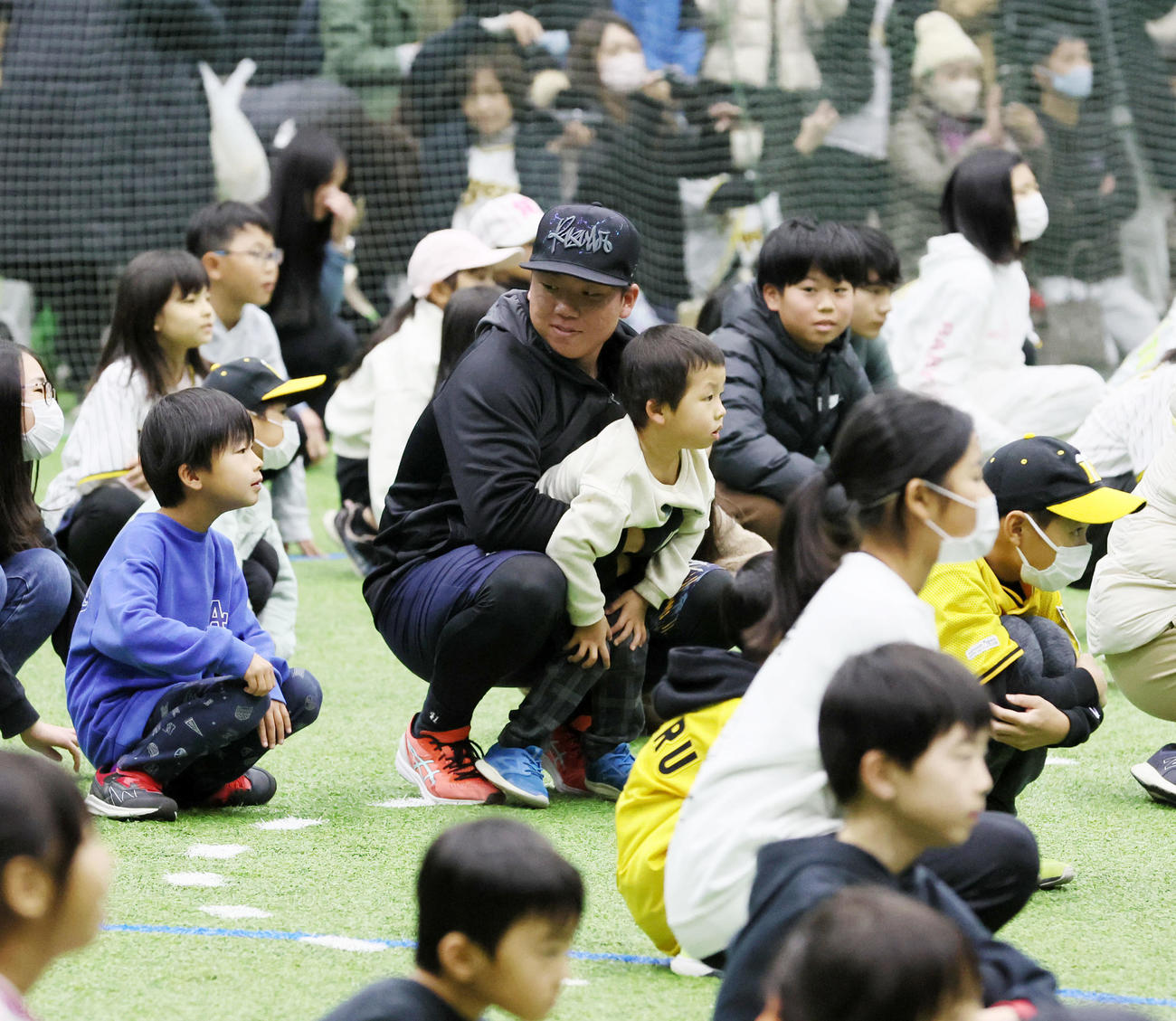 地元淡路島で近本とともに自主トレを公開した村上はその後のふれあい教室で子供たちといっしょにしゃがみ込む（撮影・加藤哉）
