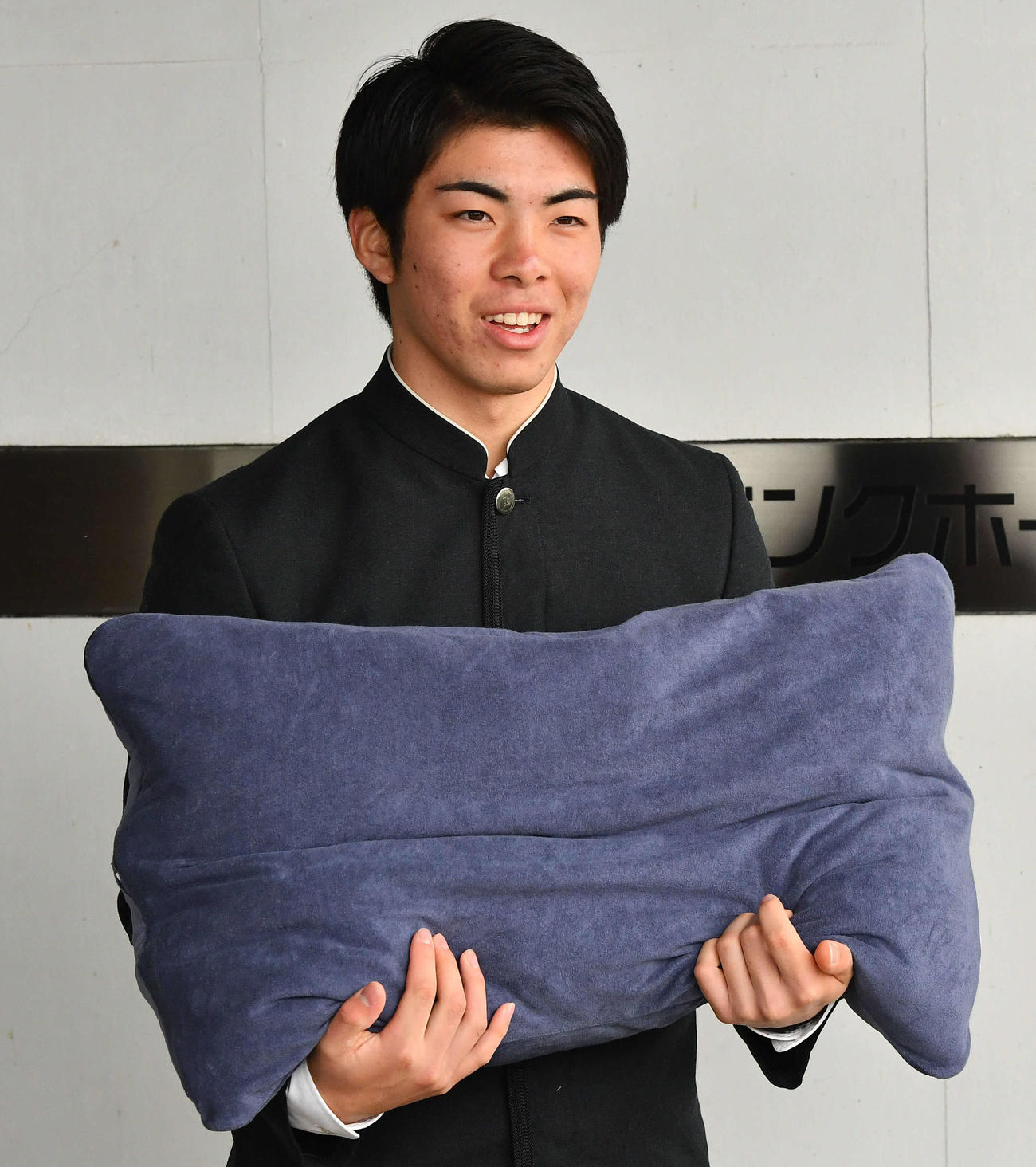 若鷹寮へ到着したソフトバンクドラフト1位の村上は、囲み取材で持参したオーダーメードの枕を見せる（撮影・岩下翔太）