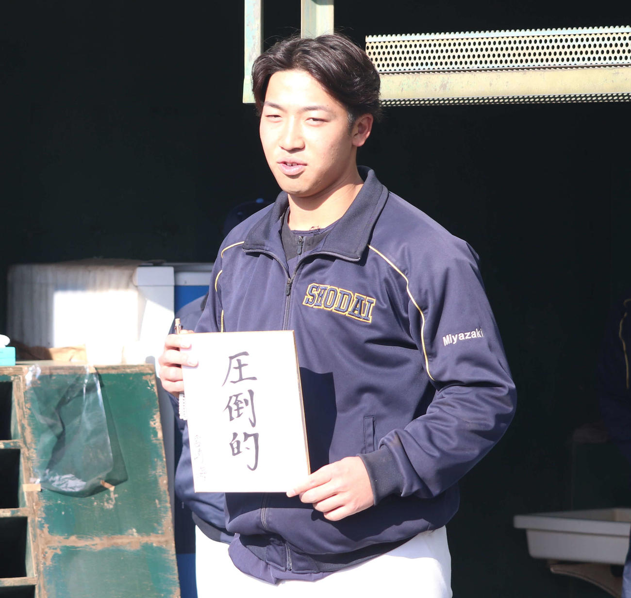 神奈川・横浜市内の横浜商大グラウンドで練習始めを行いミーティングで今年の目標「圧倒的」を記した色紙を持つ横浜商大・宮崎（撮影・佐瀬百合子）
