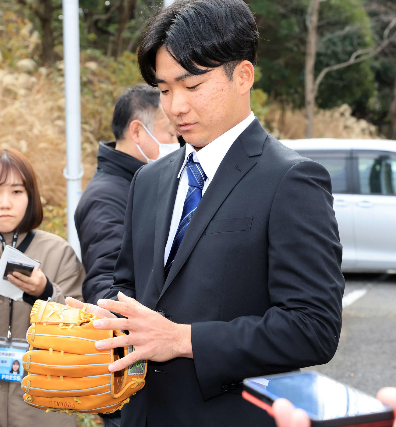 日本ハム勇翔寮に入寮した山県は、早大・小宮山監督から贈られたグラブを見つめながら報道陣の質問に答える（撮影・浅見桂子）
