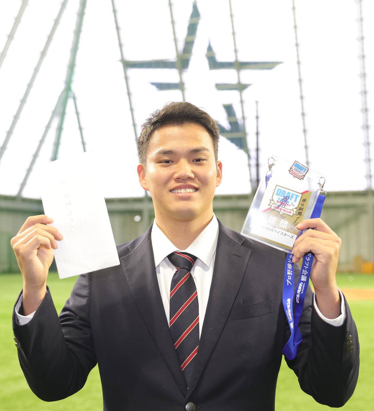 三浦監督のサイン入りドラフト会議IDと、担当の木塚スカウトから贈られた手紙を手に入寮するDeNA坂口（撮影・野上伸悟）