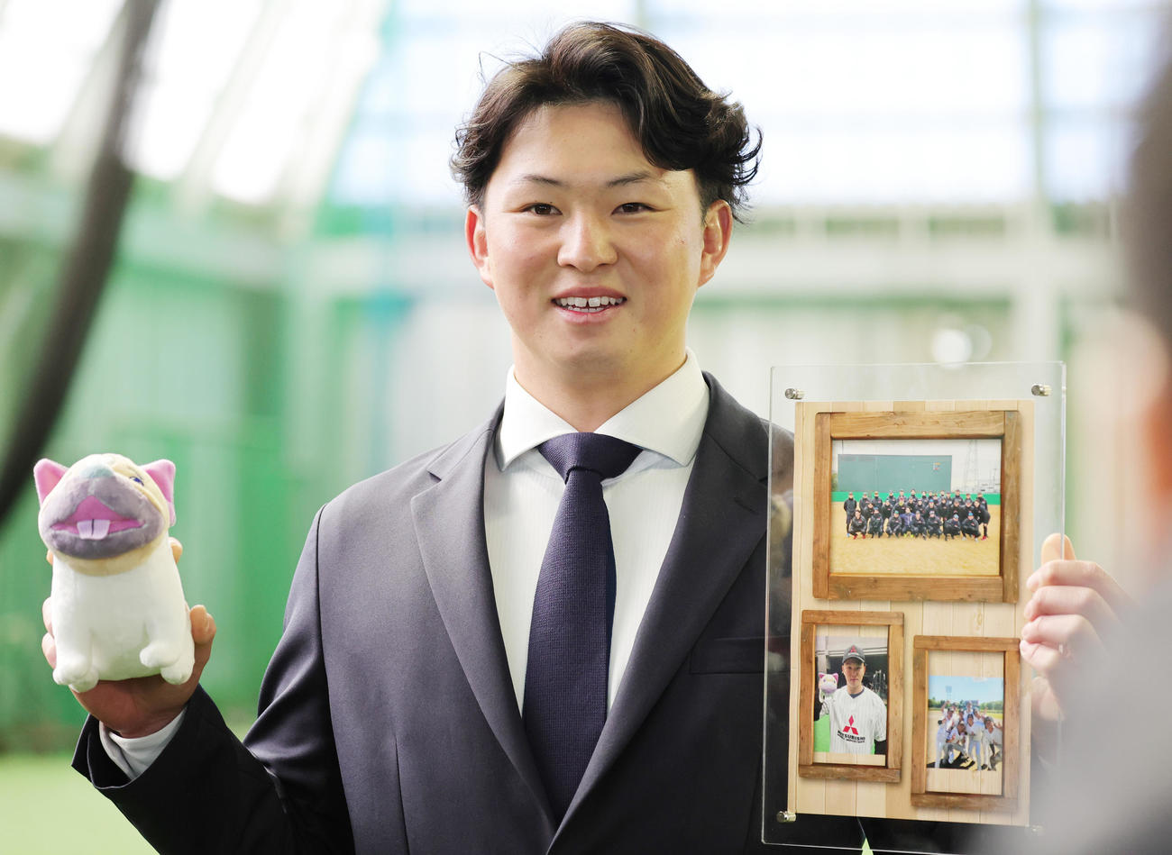 三菱重工のマスコット「サステナブルくん」と三菱重工West時代のアルバムを手に入寮したDeNA竹田（撮影・野上伸悟）