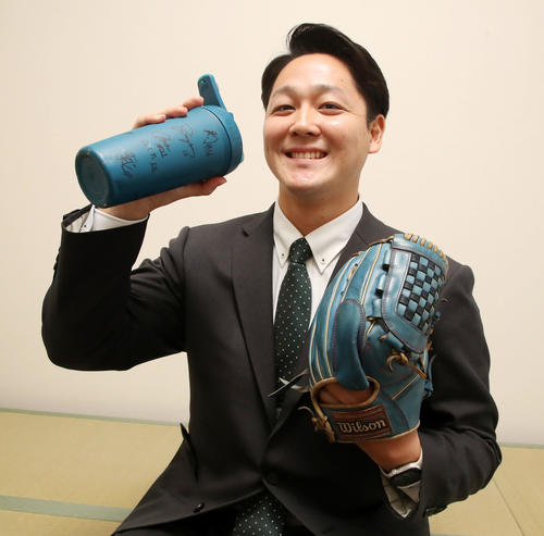 虎風荘へ入寮した木下は持参したチームメートのサインいりボトルとグラブを手に笑顔を見せる