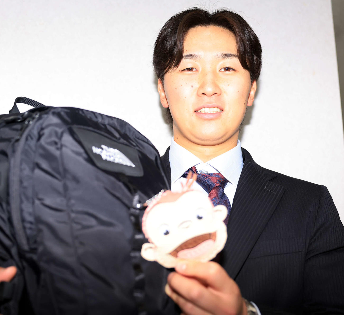 千葉ロッテマリーンズ寮に入寮し、カバンにつけたおさるのジョージを見せる宮崎（撮影・浅見桂子）