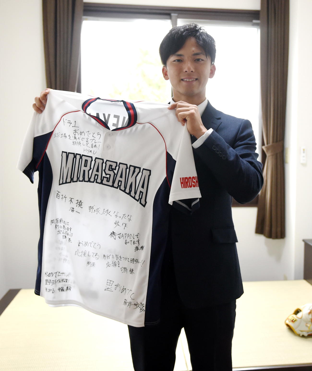 小学生時代のチームメートから贈られた寄せ書きユニホームを持つ楽天ドラフト1位の宗山（撮影・山田愛斗）