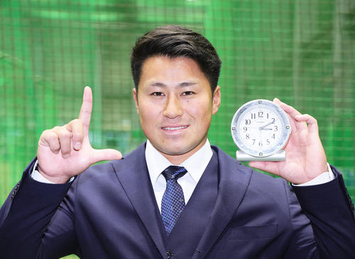 入寮し、お気に入りの目覚まし時計を手に笑顔を見せる西武ドラフト2位大商大・渡部聖(撮影・足立雅史)