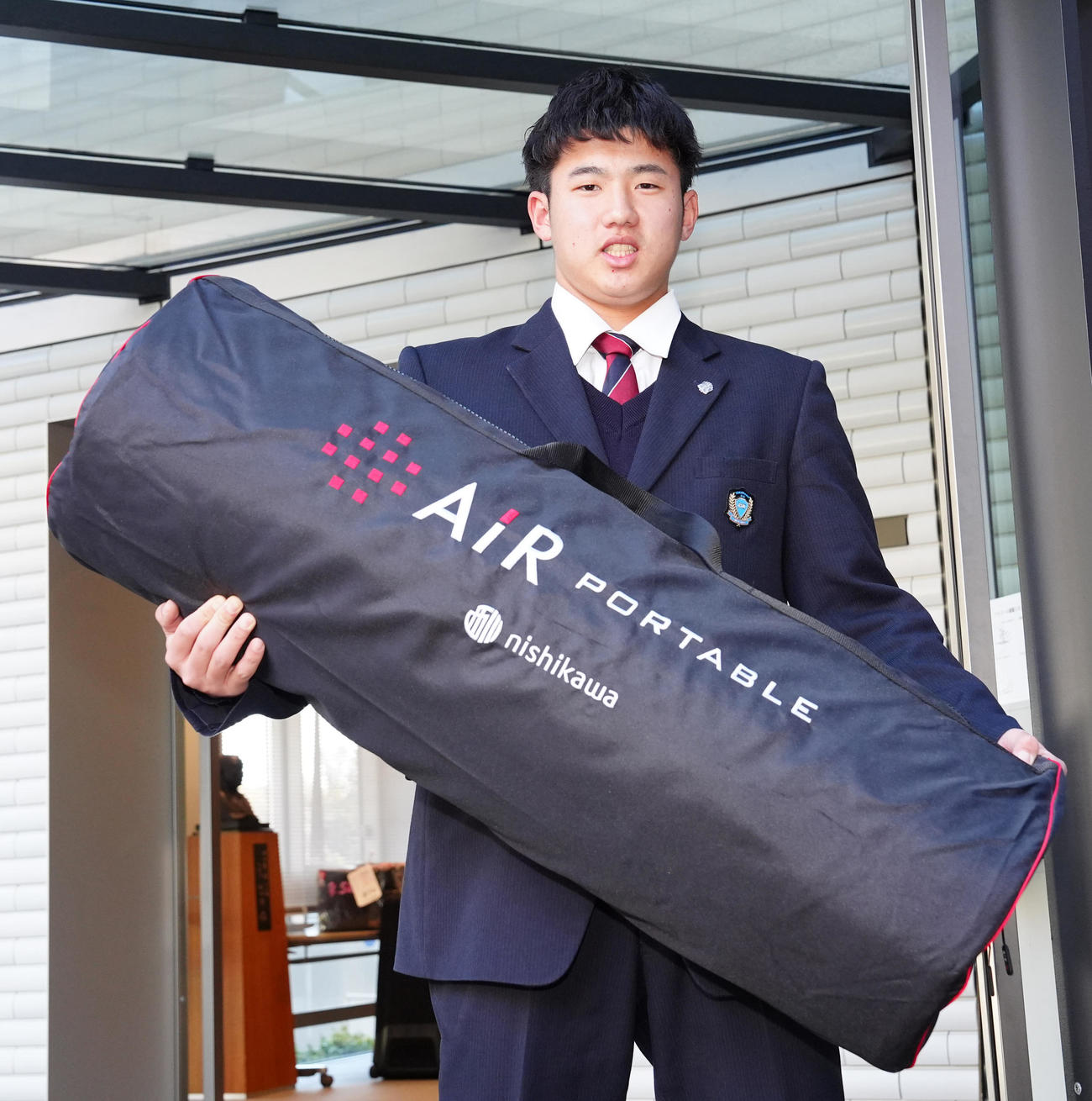 入寮し持ち込んだ寝具を手にする巨人ドラフト1位の石塚（撮影・江口和貴）