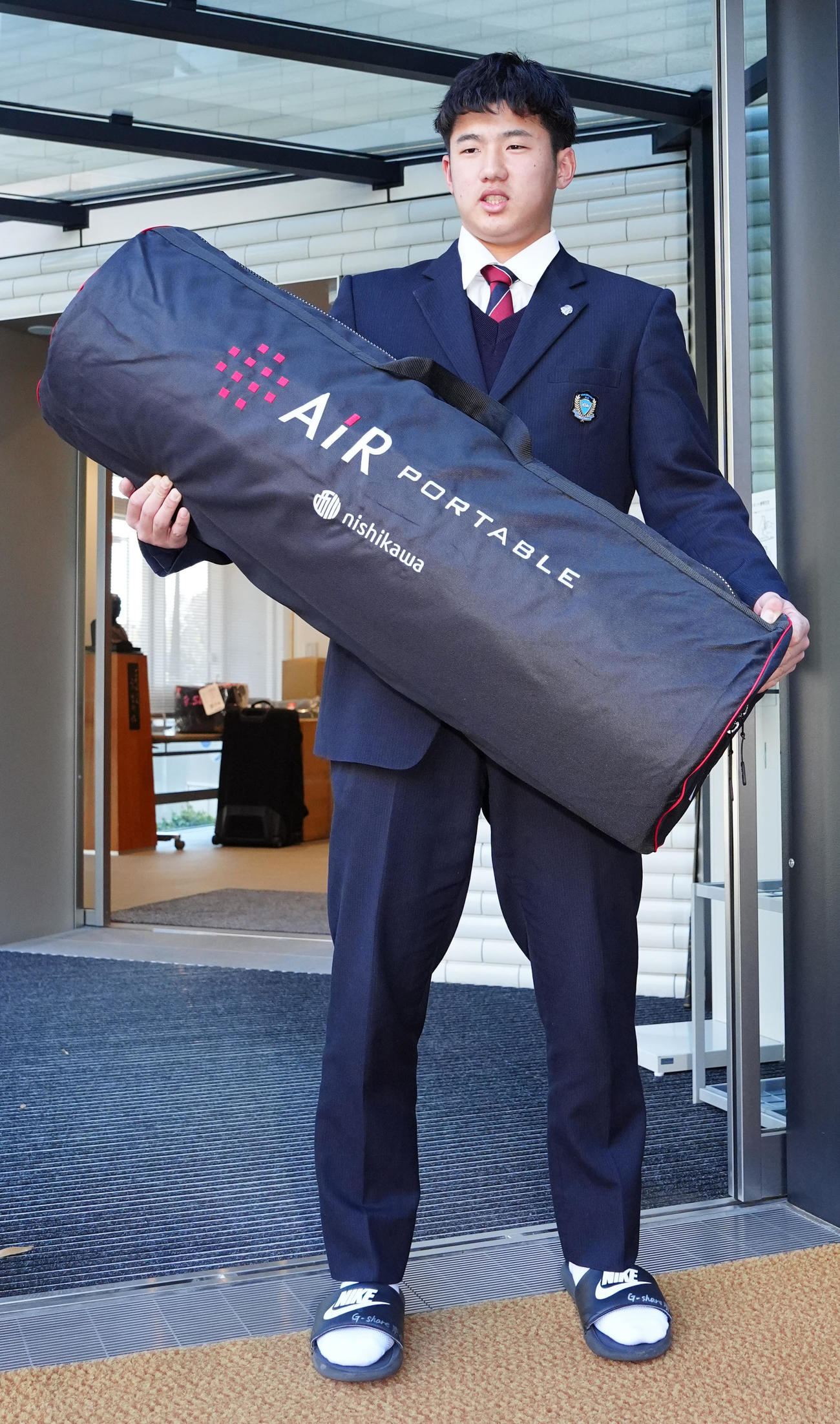 入寮し持ち込んだ寝具を手にする巨人ドラフト1位の石塚（撮影・江口和貴）