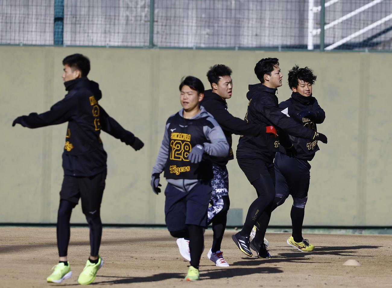 新人合同自主トレが始まり、ウオーミングアップする伊原（右端）ら阪神新人選手（撮影・藤尾明華）