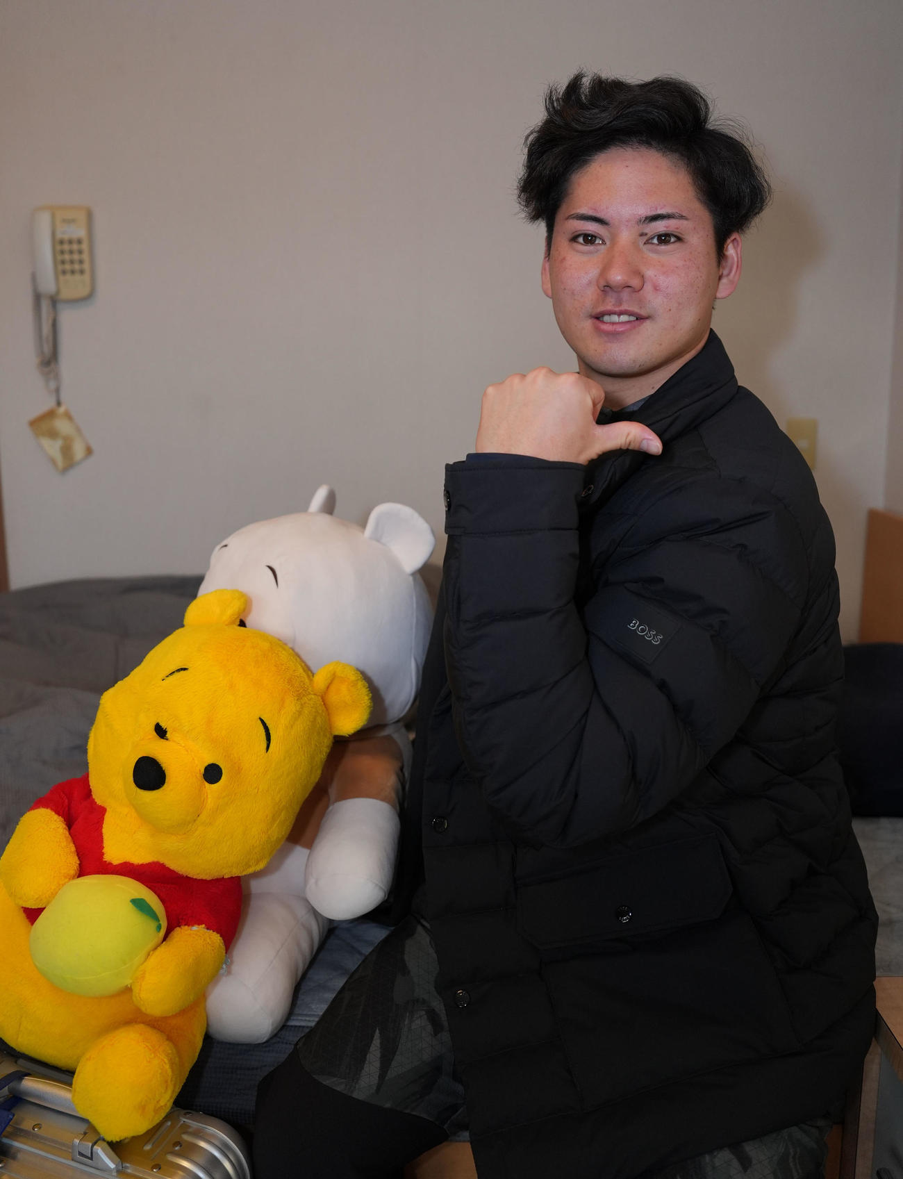 大谷翔平と同じブランドのジャケットを着こなし高橋宏からプレゼントされたスーツケースとプーさんのぬいぐるみを持参し入寮する金丸（撮影・森本幸一）