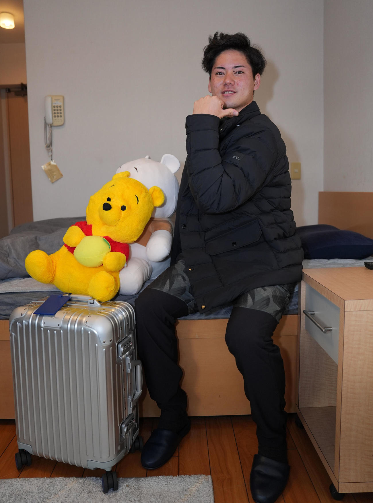 大谷翔平と同じブランドのジャケットを着こなし高橋宏からプレゼントされたスーツケースとプーさんのぬいぐるみを持参し入寮する金丸（撮影・森本幸一）