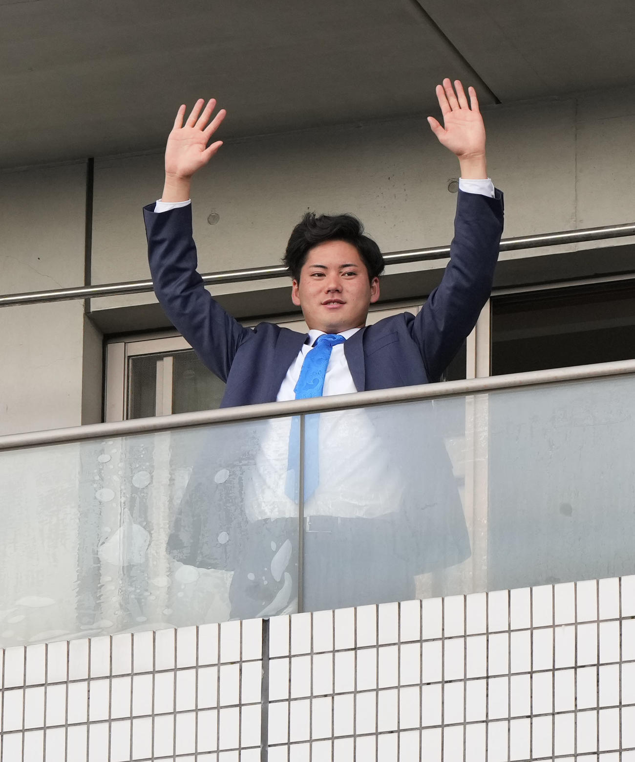 入寮しテラスから手を振る金丸（撮影・森本幸一）