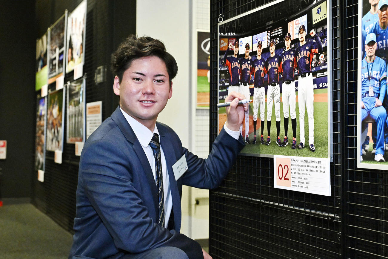 野球殿堂博物館に飾られた自身の写真にサインをする中日ドラフト1位の関大・金丸（撮影・滝沢徹郎）