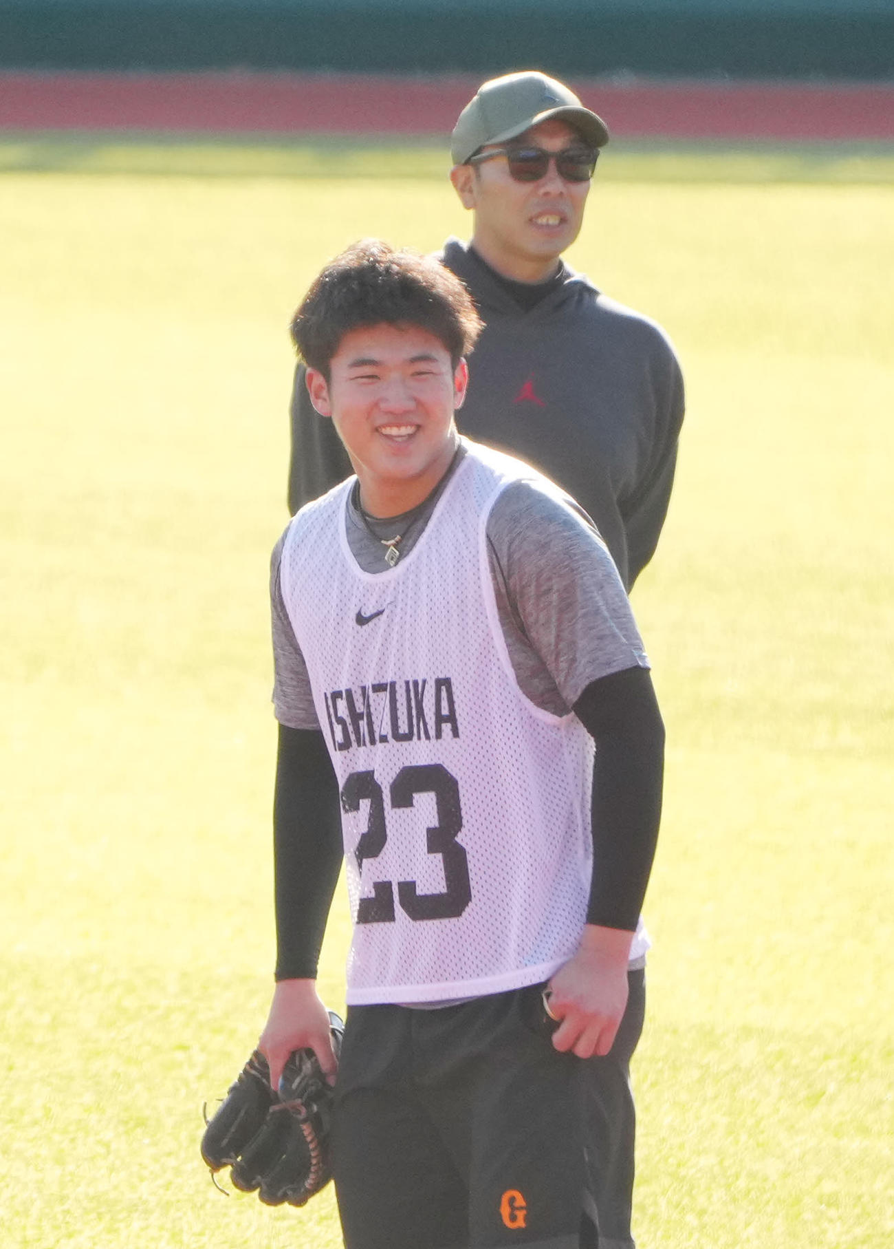 巨人新人合同自主トレに臨む石塚。後方は視察する阿部監督（撮影・江口和貴）