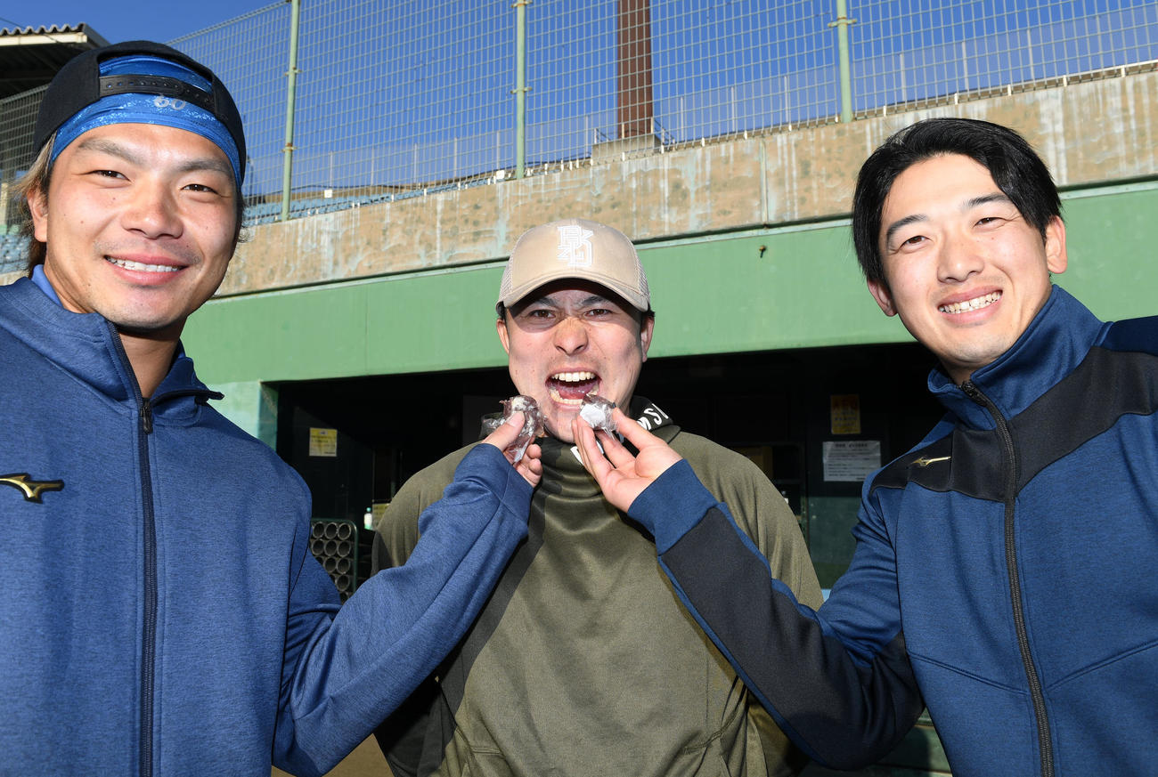 DeNA知野（左）、山本（右）から藤戸まんじゅうを食べさせてもらう佐野（撮影・前岡正明）