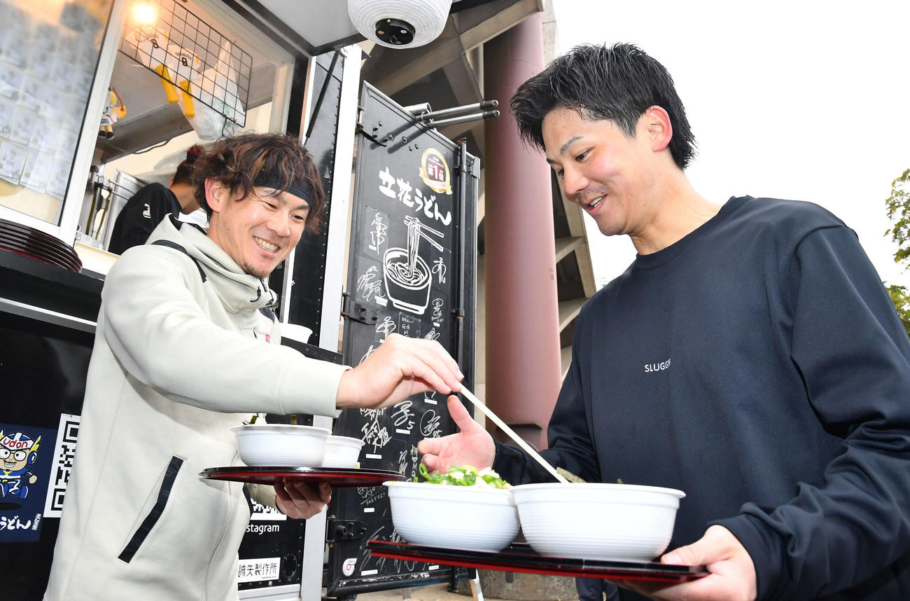 昼食のうどんを受け取り、緒方（右）に箸を渡すソフトバンク牧原大（撮影・岩下翔太）