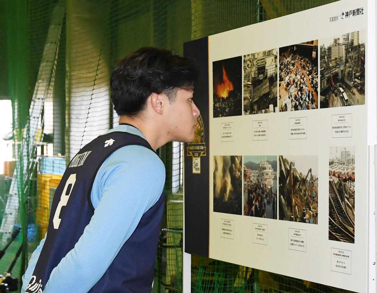 展示された阪神・淡路大震災の写真を見るオリックス麦谷。奥は山中（撮影・前岡正明）