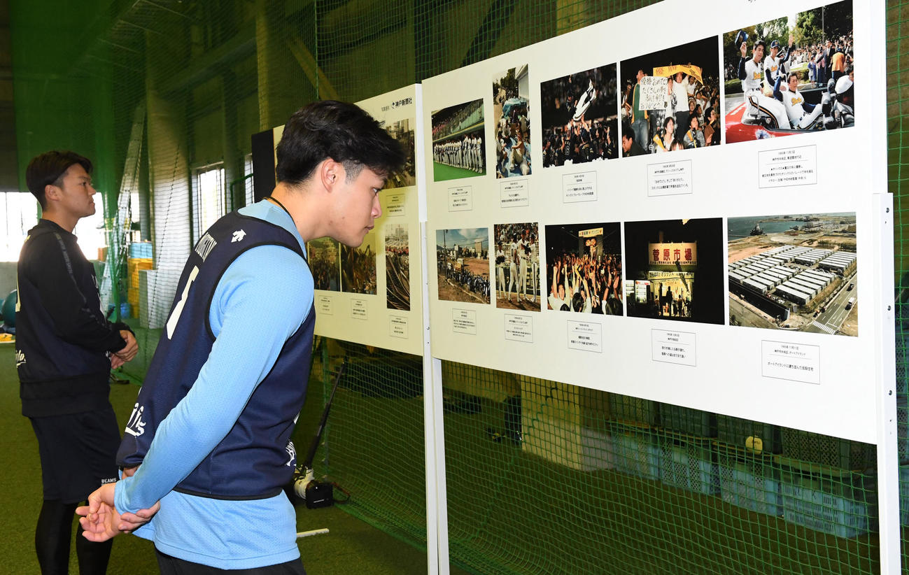 展示された阪神・淡路大震災の写真を見るオリックス麦谷。奥は山中（撮影・前岡正明）