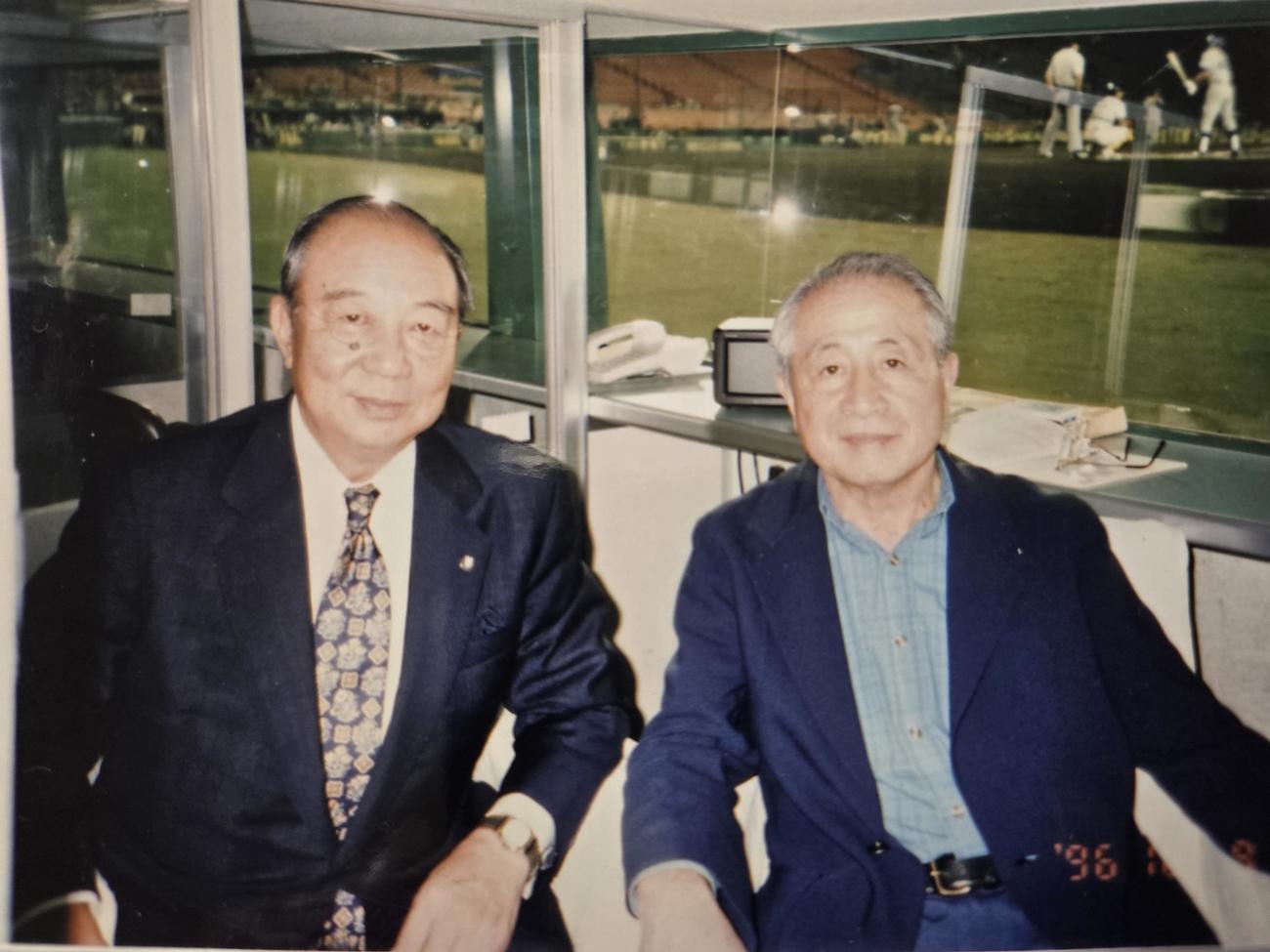 1996年10月9日の阪神対中日戦（甲子園）のネット裏ブースで写真に収まった谷村友一氏（右）と三好一彦氏（提供写真）