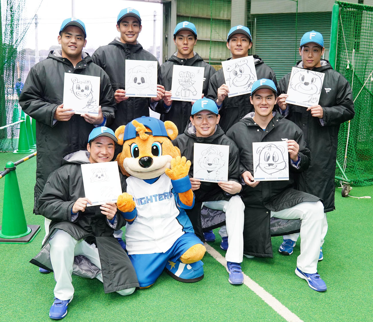 カビーの似顔絵を手に笑顔を見せる日本ハム新人選手たち。前列左から山縣、浅利、藤田、後列左から川勝、清水大、柴田、山城、渋谷（撮影・横山健太）