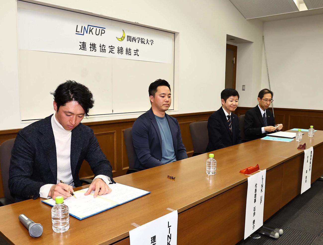 LINK UP理事の近本（左）は連携協力協定書にサインする（撮影・上田博志）