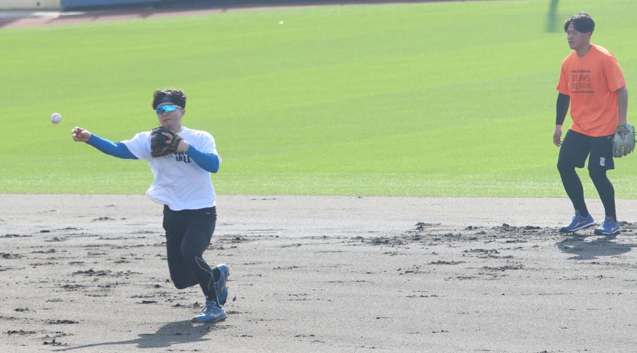 先乗り自主トレでノックを受ける日本ハム郡司。右は吉田（撮影・永野高輔）