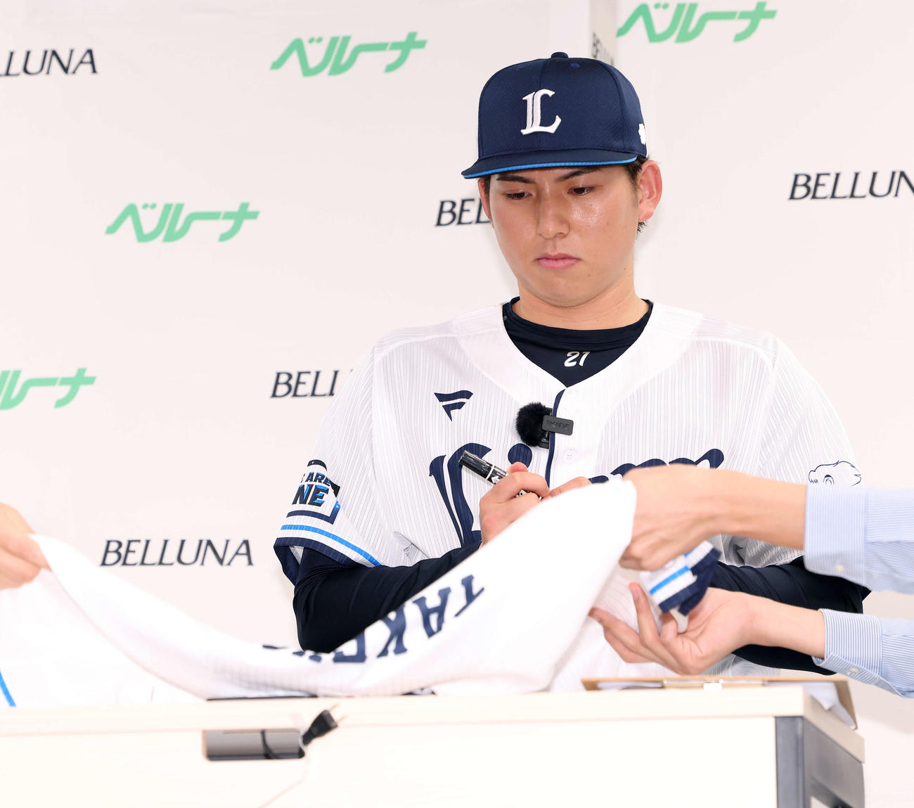 ユニホームにサインする西武武内（撮影・河田真司）